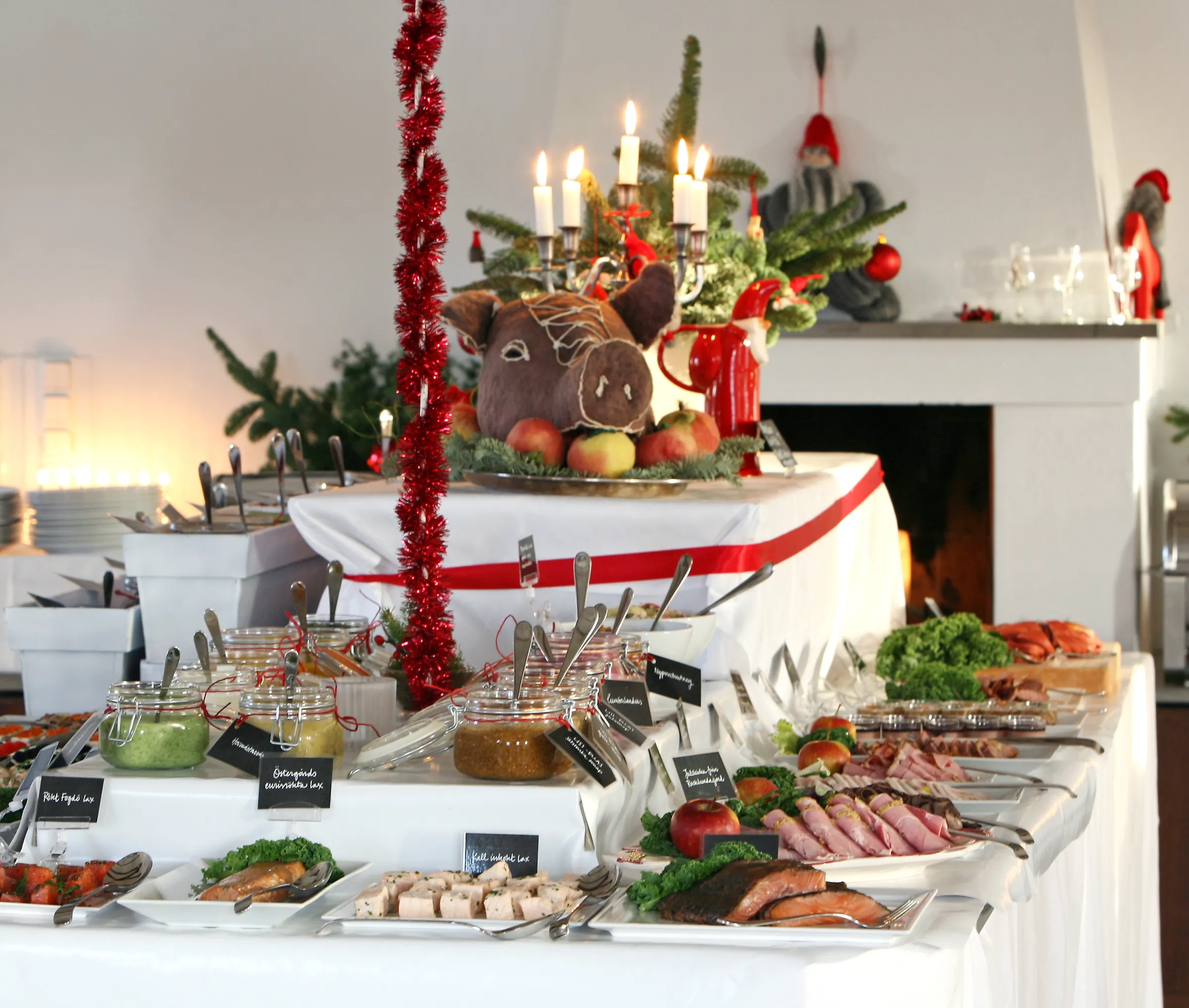 Ett julbord med lax, skinka och sill under tända ljus och en julgrisdekoration.