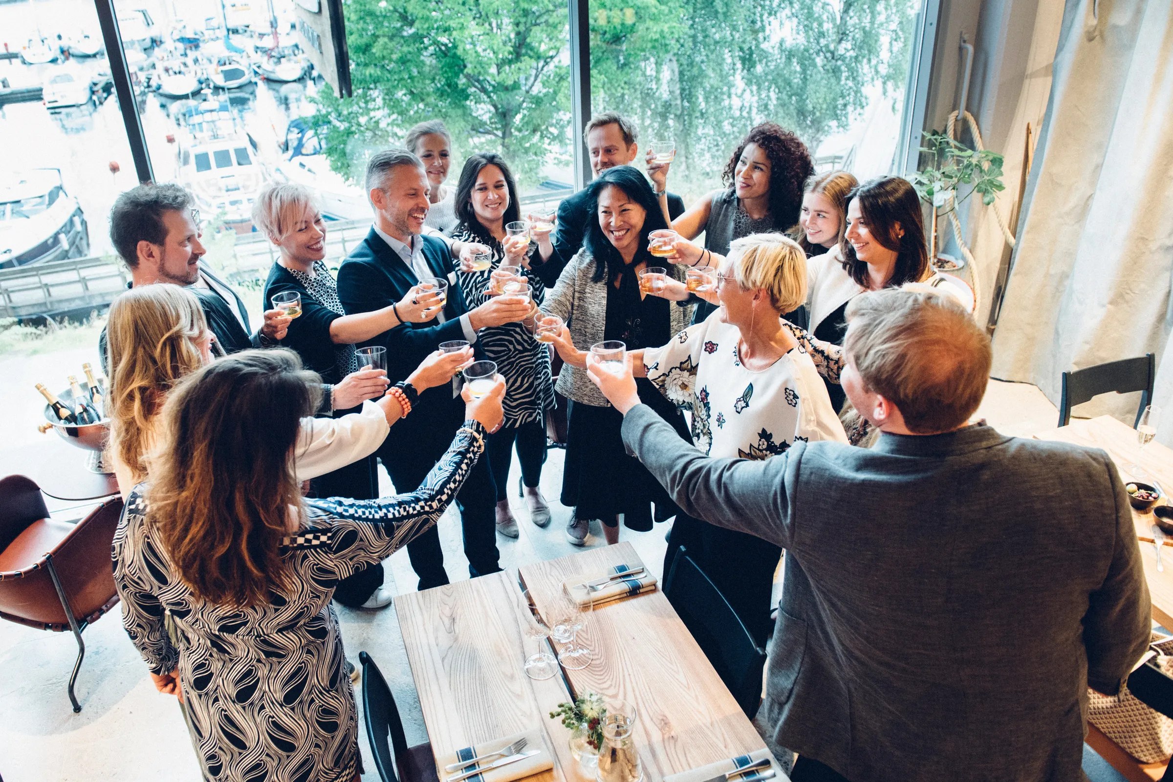 Ett sällskap skålar tillsammans vid stora fönster i Vikingamuseets restaurang.